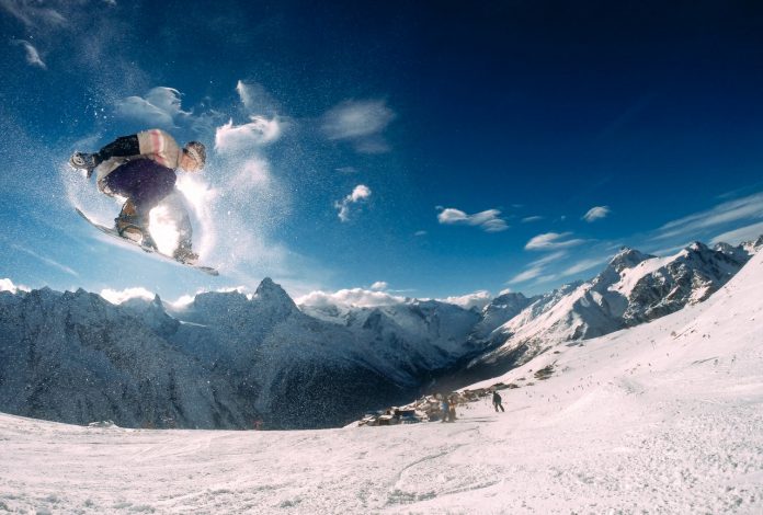 Person står på snowboard ned ad bjerg